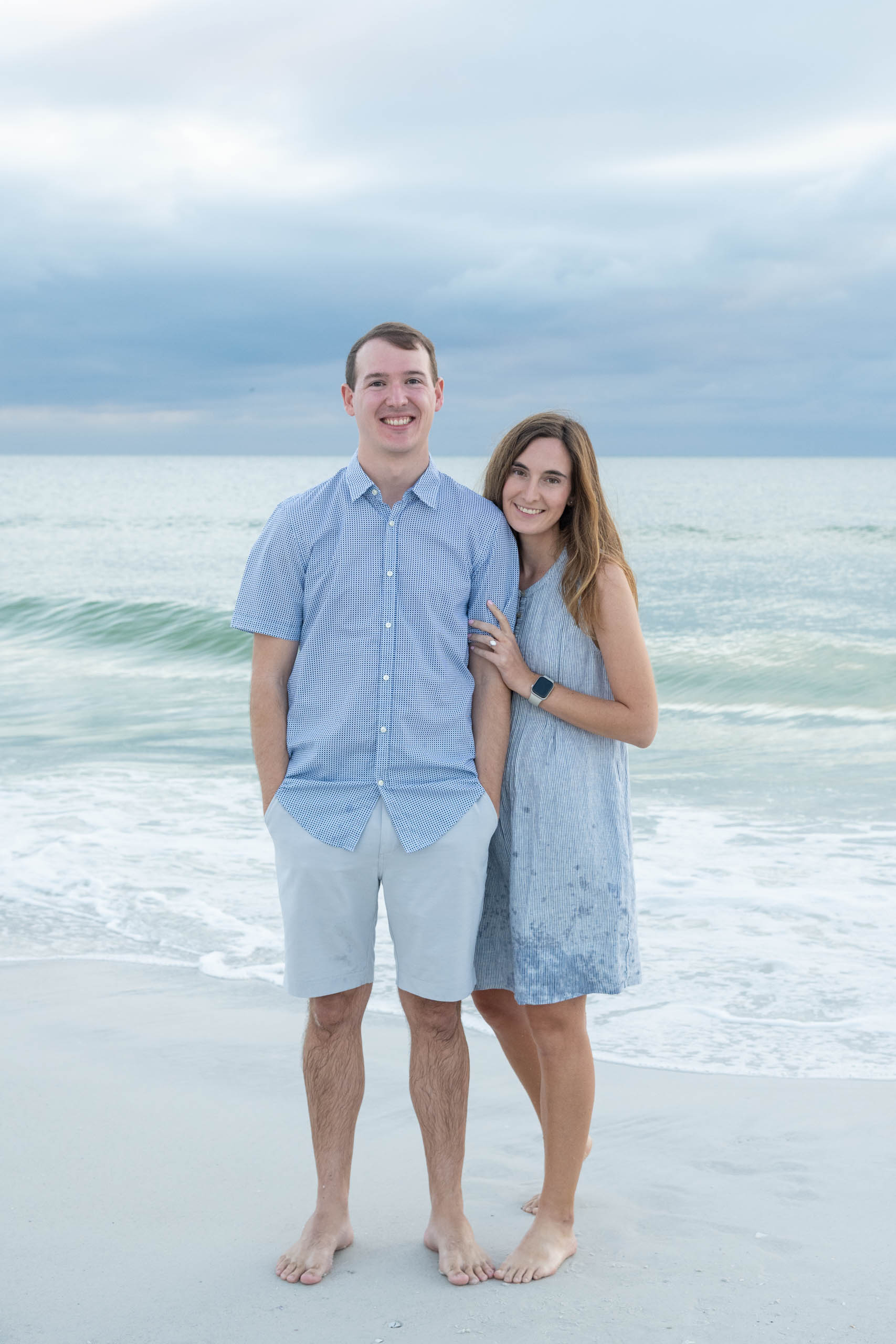 newly engaged couple smile as woman hugs her fiance's arm on Lido Beach