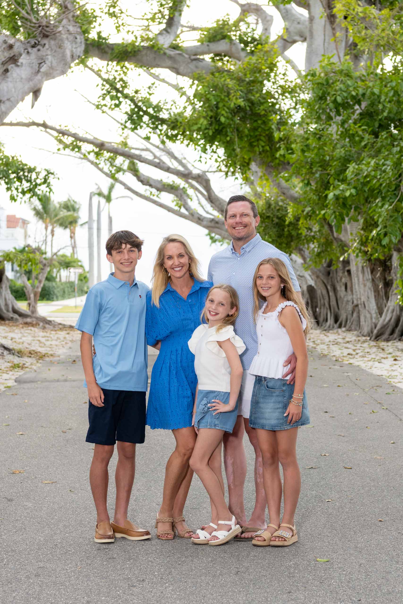 family of five, all dressed in blue and white, stand in the middle of Banyan Street