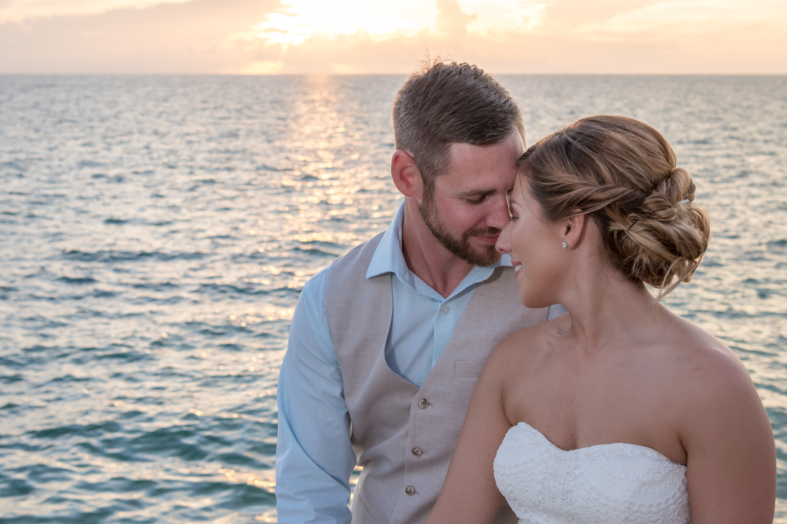 bride and groom sit quietly with their foreheads together, relaxing as the sun sets behind them