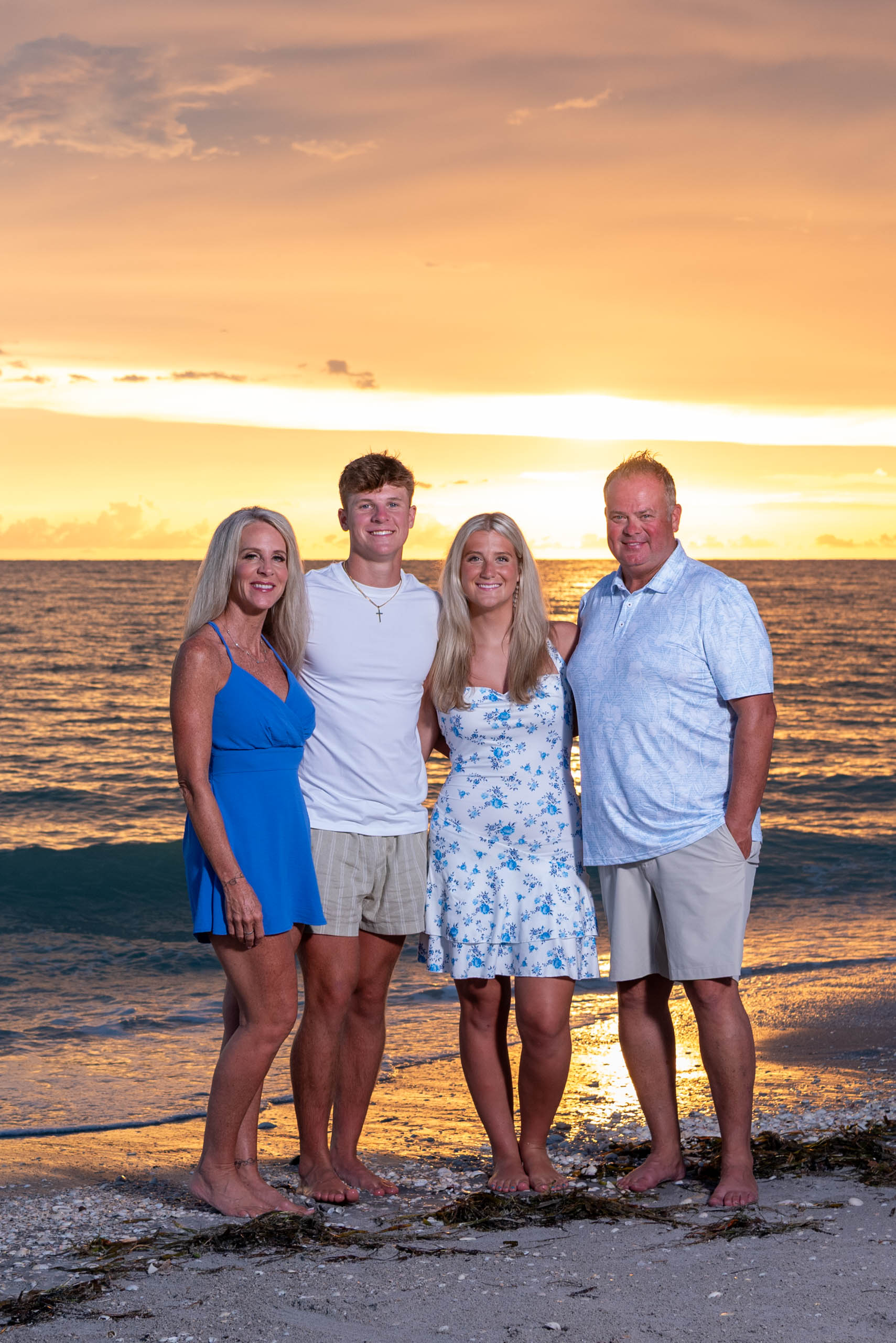 parents with their teenage children on the beach with a brilliant orange sunset behind them