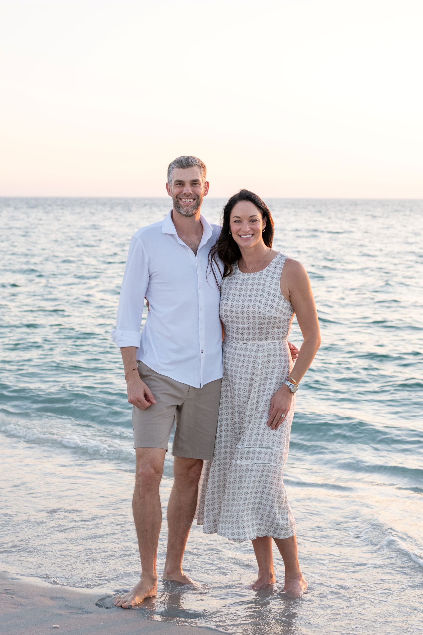 mom and dad share a moment to get the picture taken with their feet in the water