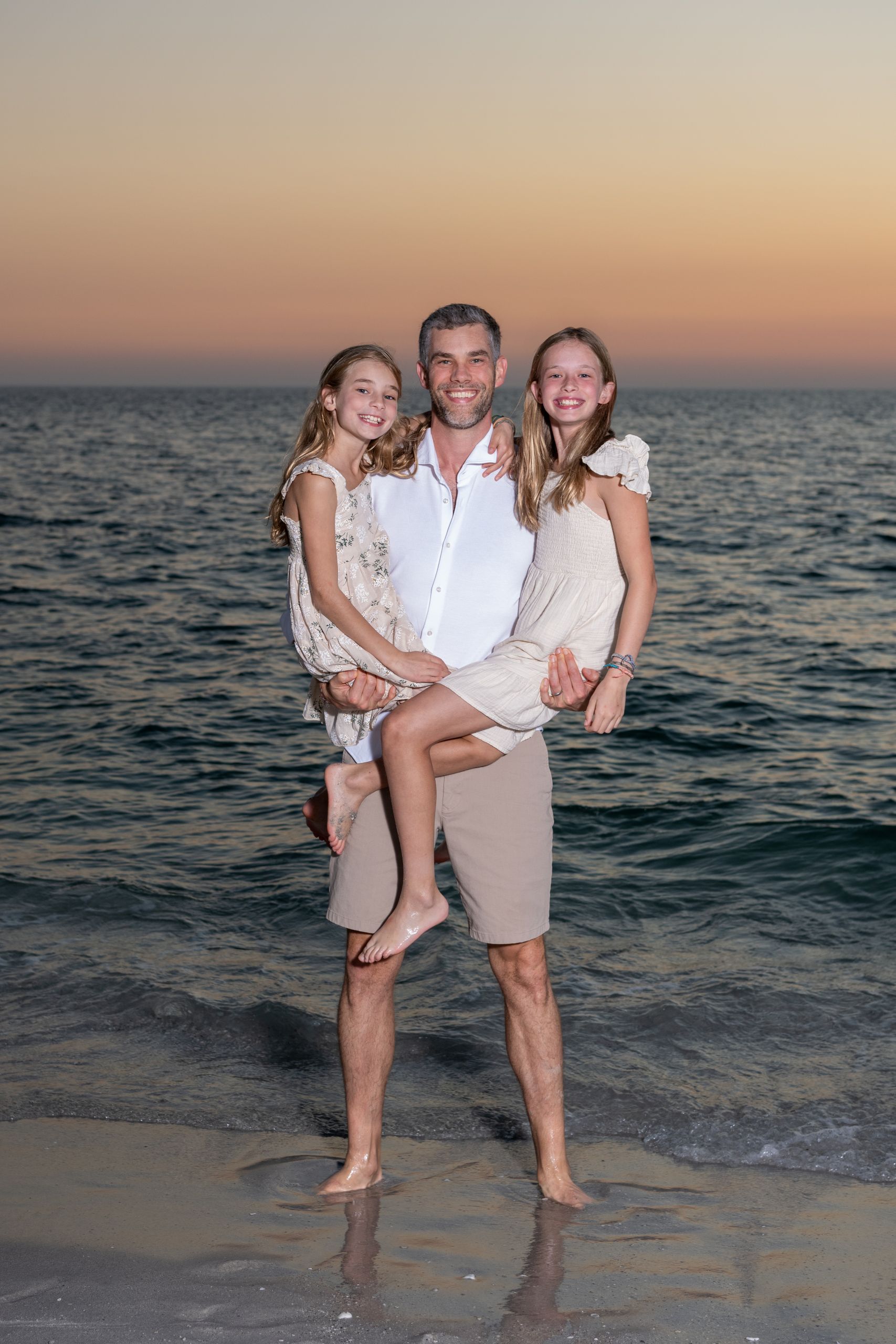dad holds his two daughters in his arms, smiling