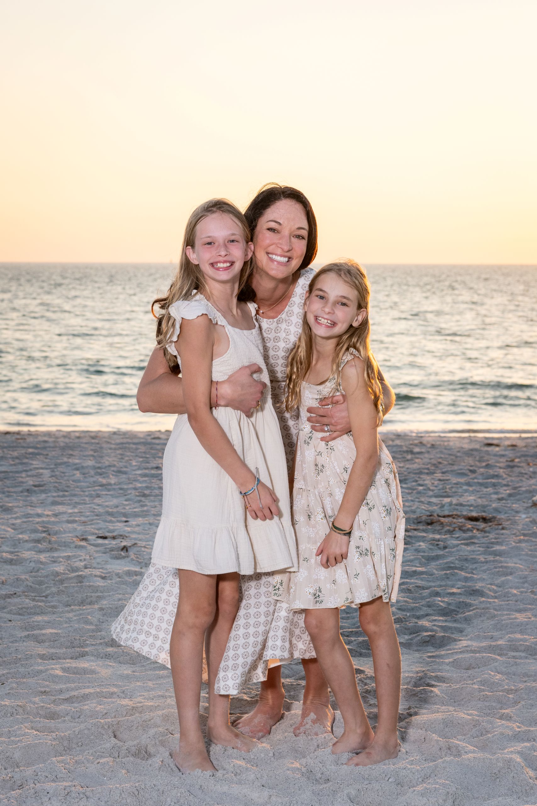 mom smiles as she hugs her two daughters close