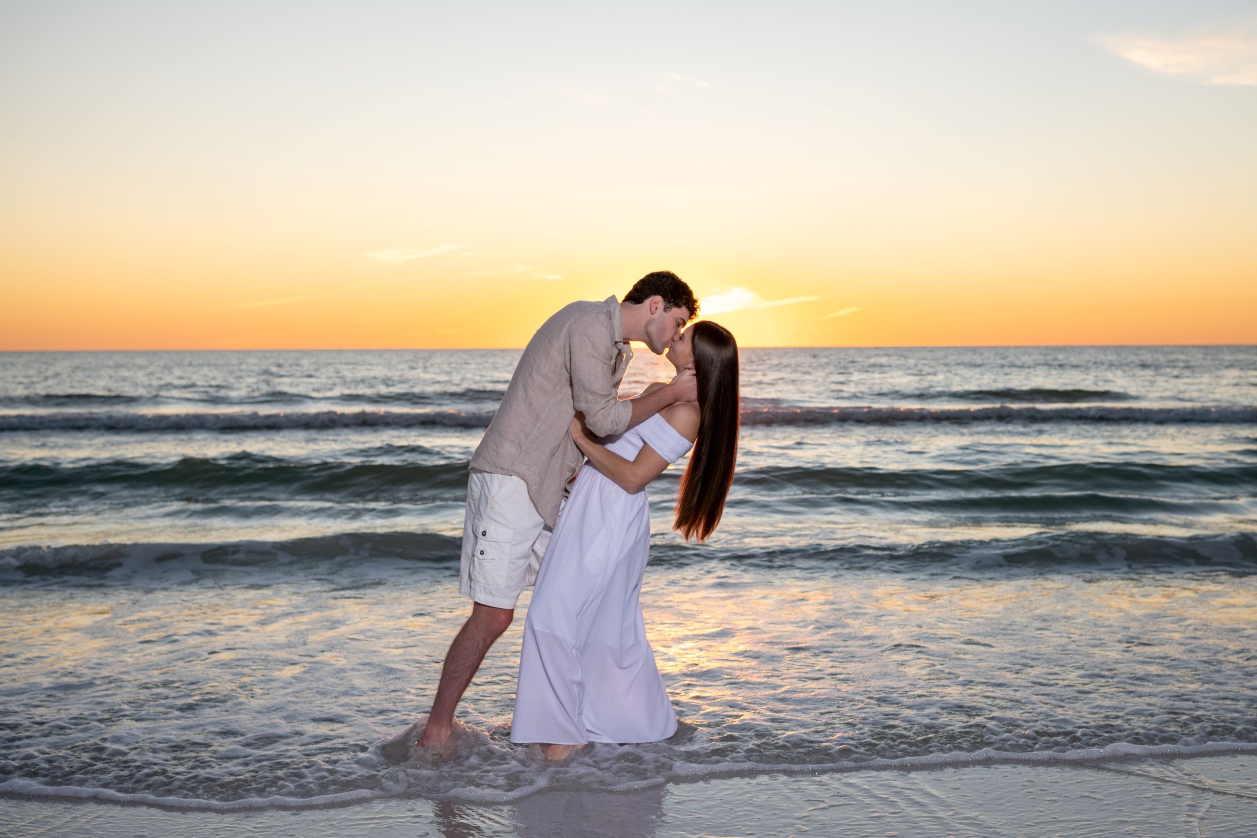 couple kiss as the sun sets behing them