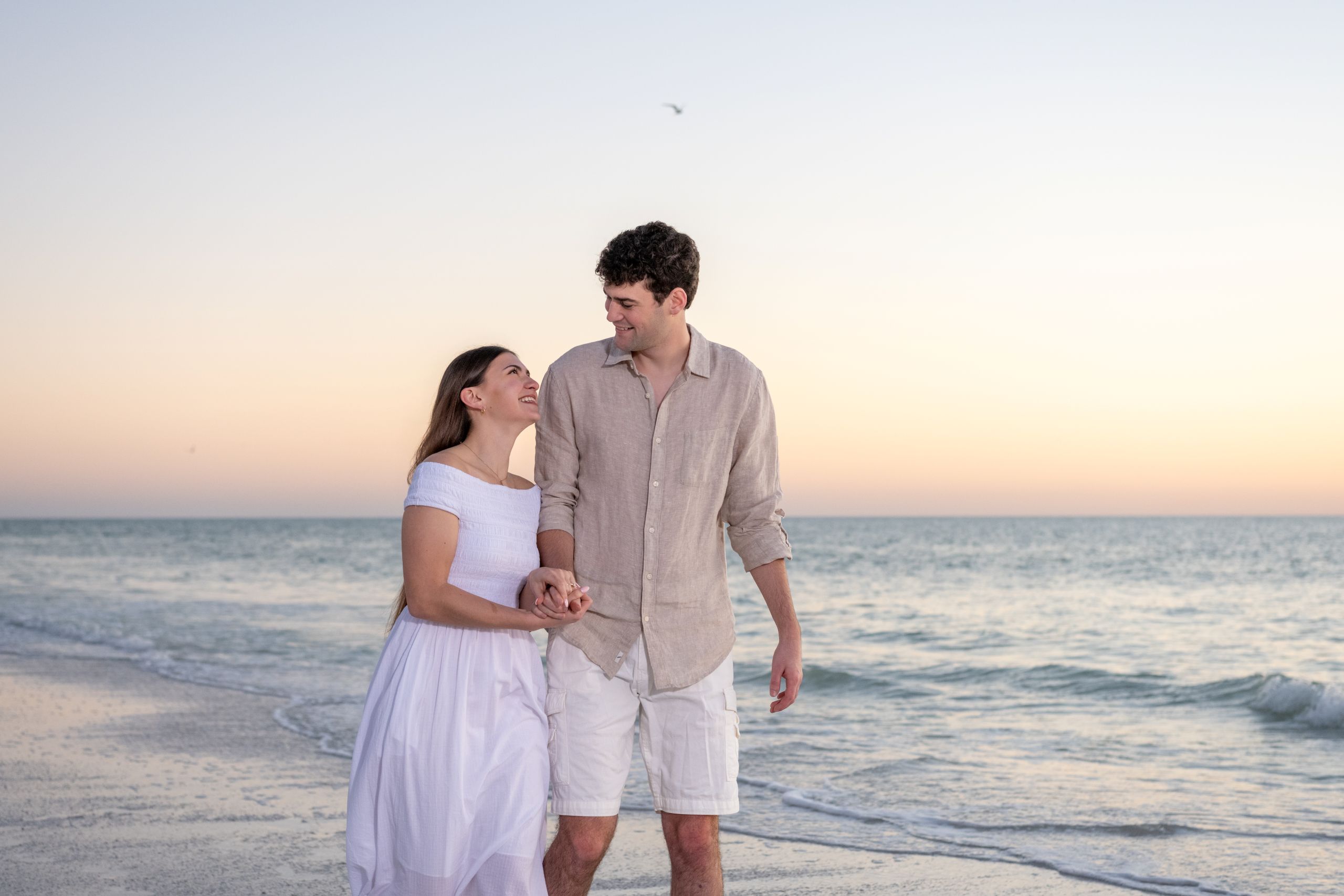 couple walk along the beach looking lovingly at each other
