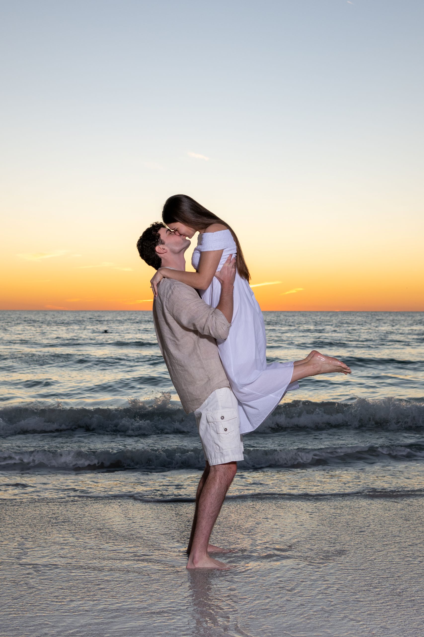 guy lifts his fiance up in the air and she leans over to kiss him