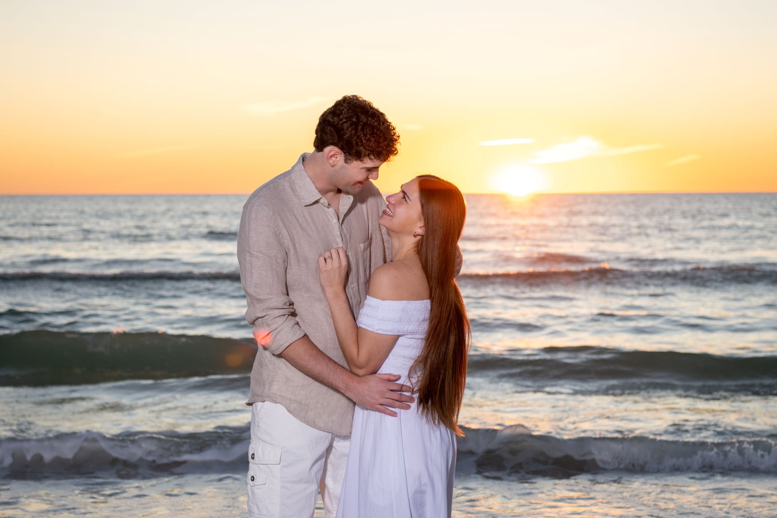 couple look each other in the eyes as the sun sets behind them