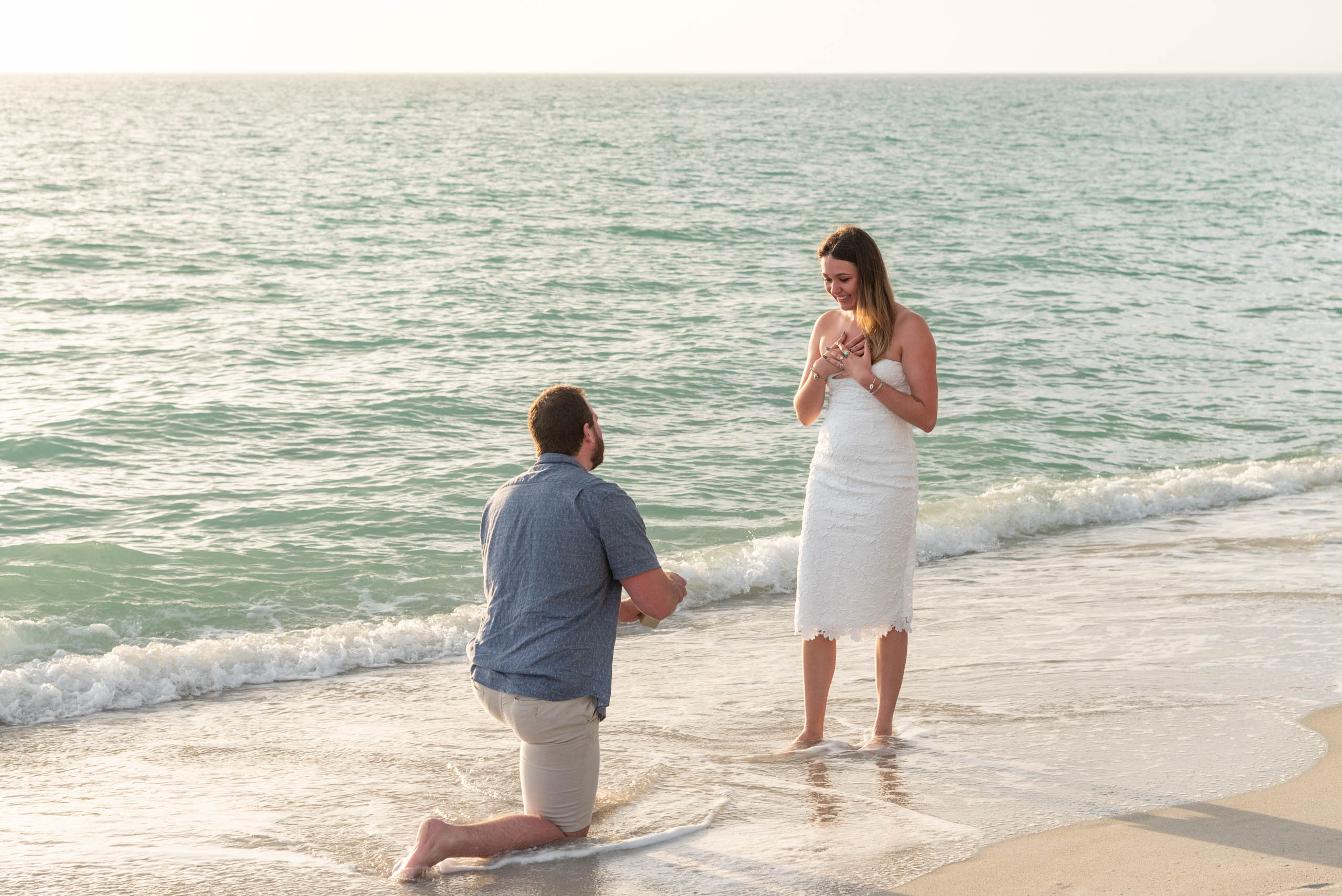 guy on his knee proposing to his girlfriend on the beach around sunset