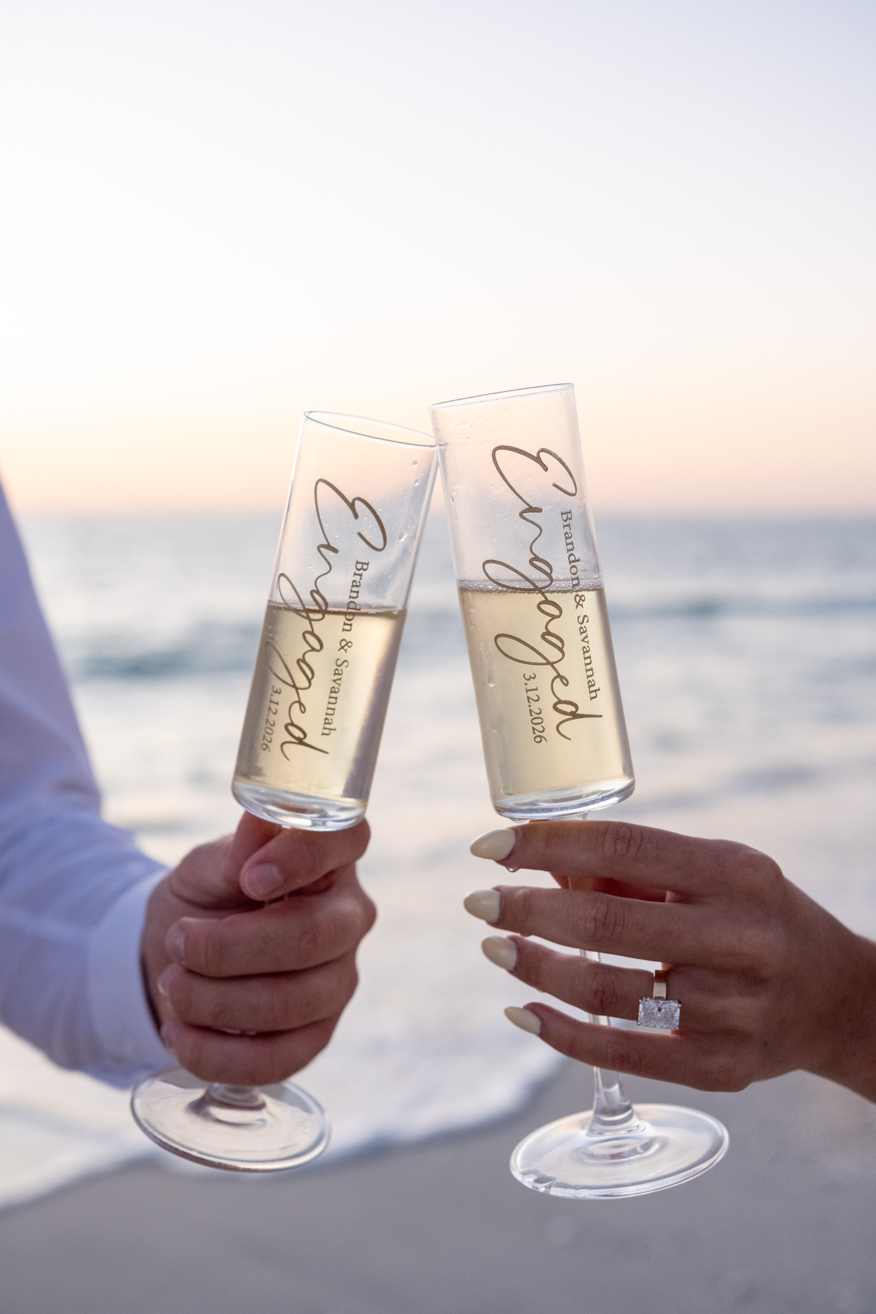 customized champagne glasses clinking together at sunset on the beach