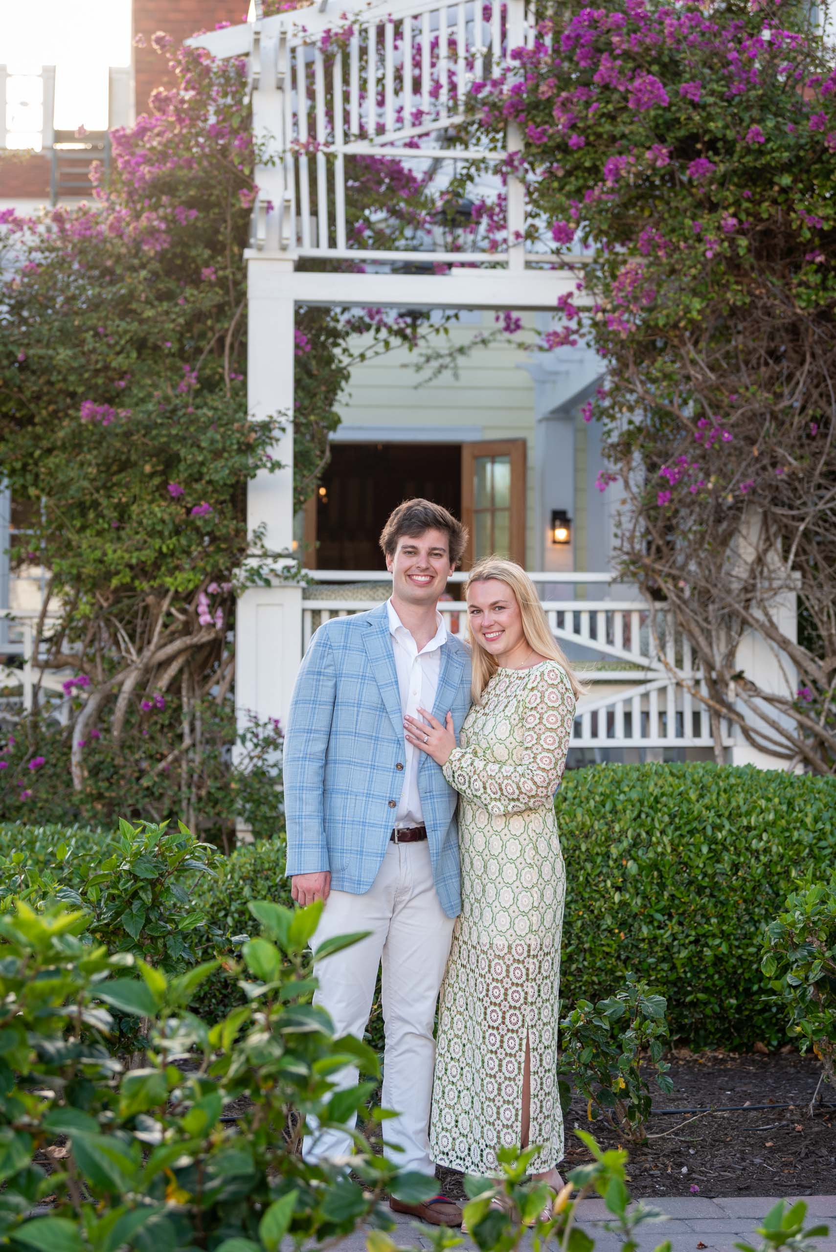 engaged couple at the Gasparilla Inn in front of the outdoor patio with bougainvillea around it