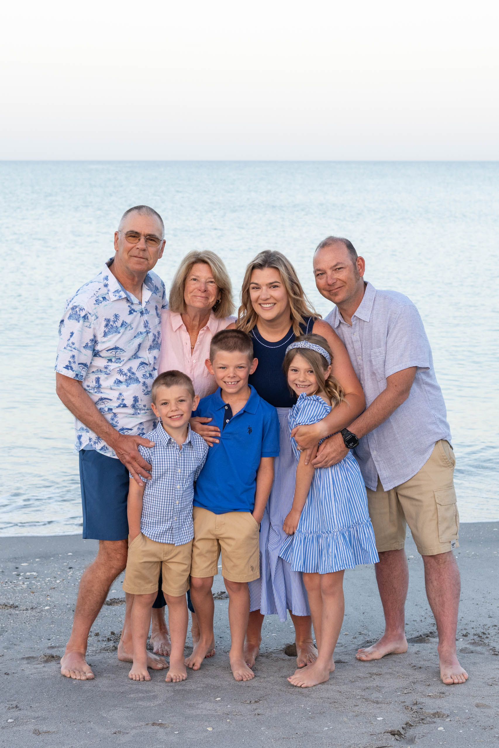 family hugs together smiling on the beach in the morning