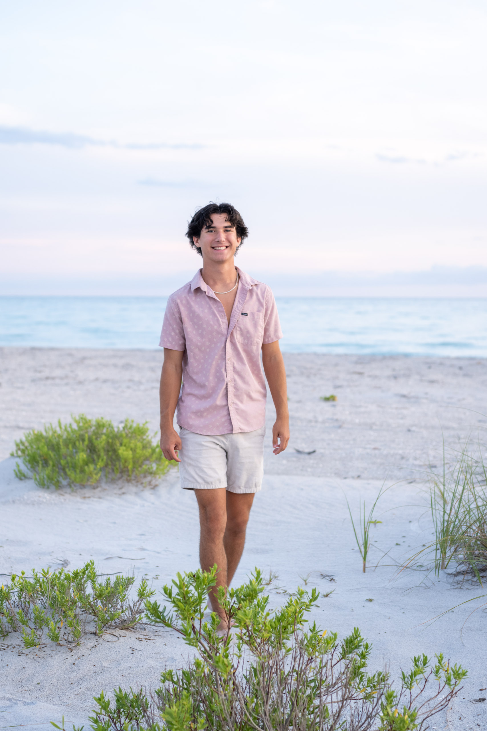 senior boy dressed in pink on the beach