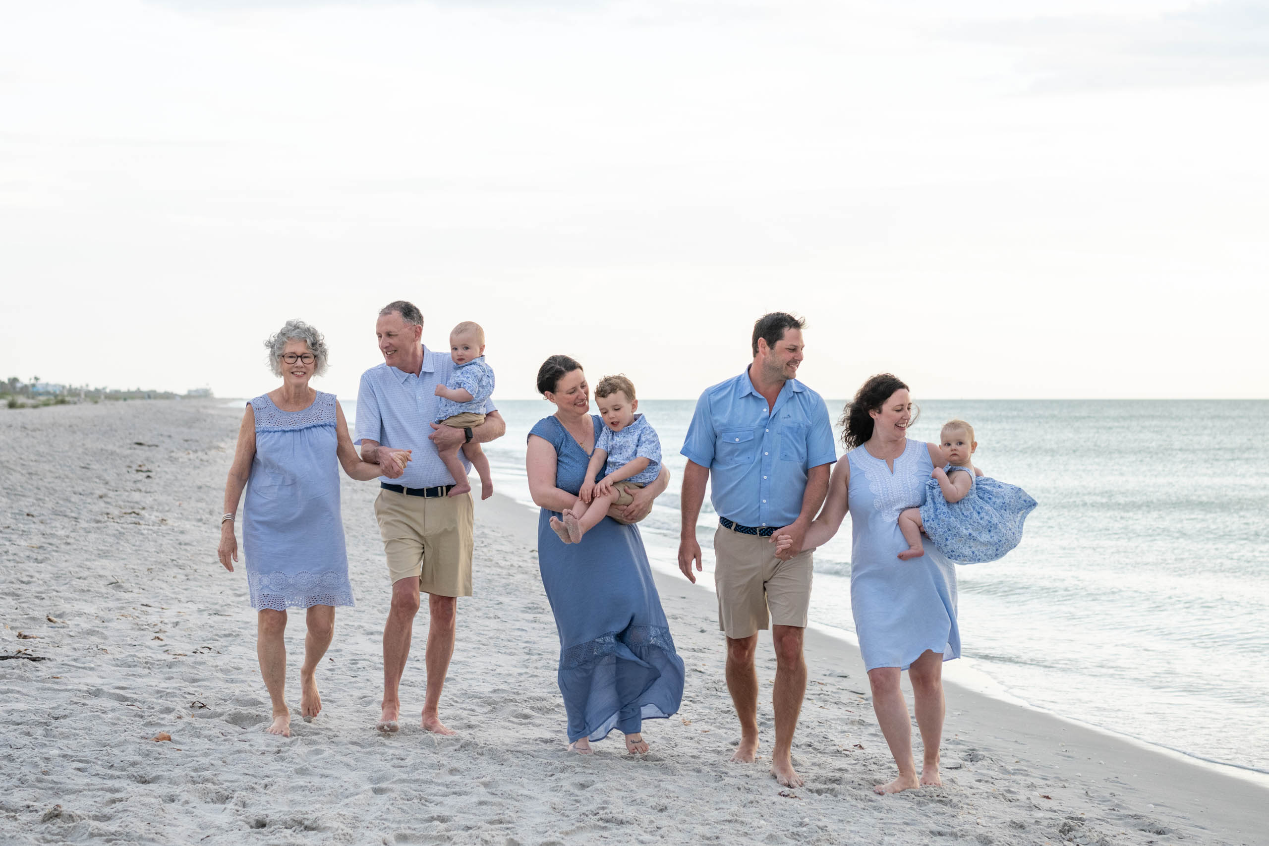 family holding hands and laughing as they walk along the beach